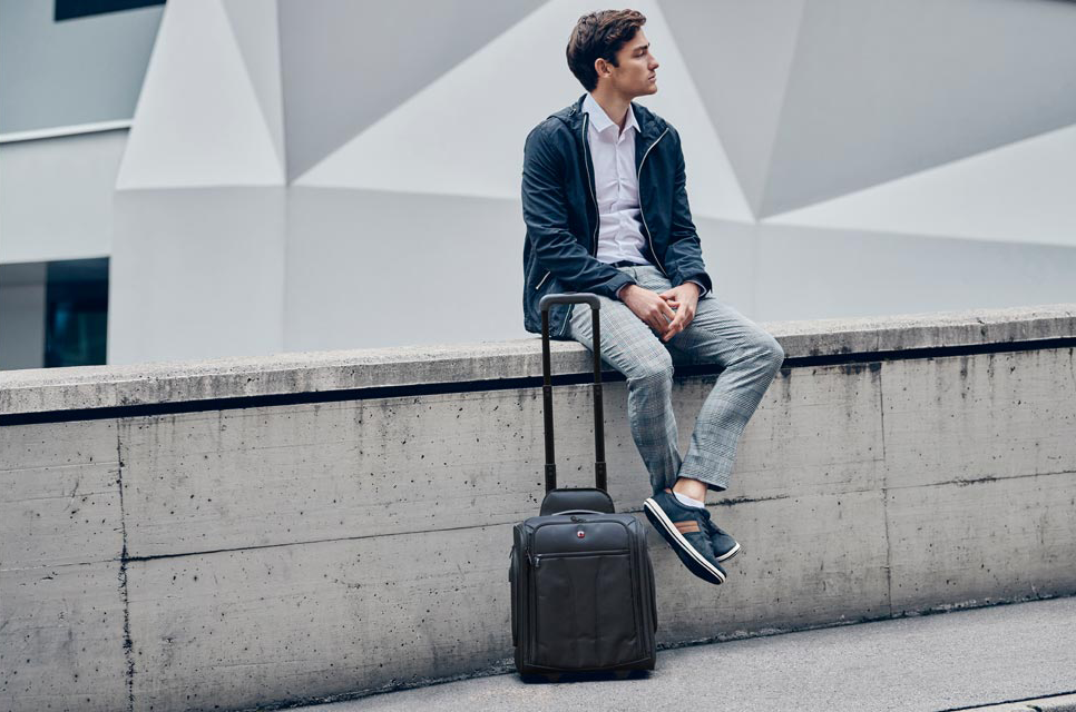 Man sitting on a wall with a Wenger Trolley bag