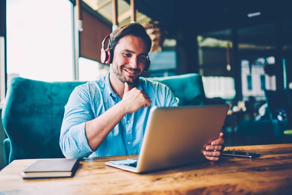 Skurio man sits with laptop looking happy